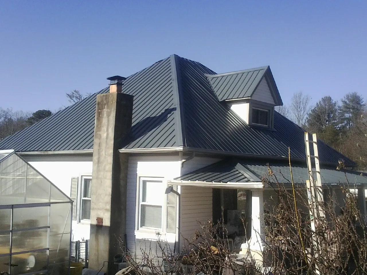 Dark blue standing seam metal roof on a white farmhouse with dormer — Slate & Tile Roof Repair by Roofing Brothers in Darrington