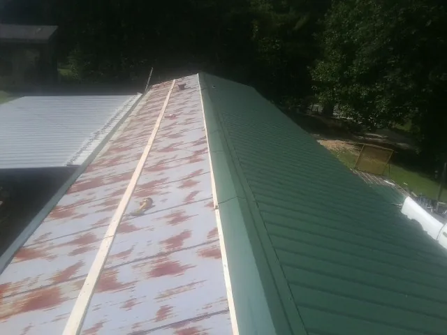 Old rusted panels beside newly installed green metal roofing — Wind Damage Roof Repair by Roofing Brothers in Darrington