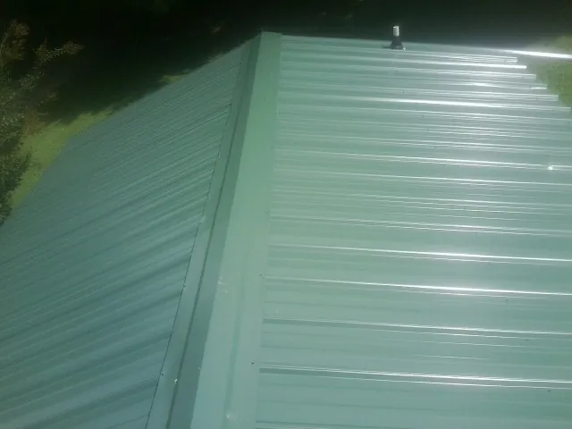 New green metal panels meeting at the ridge of a roof — Flat Roof Repair work by our crew in Darrington