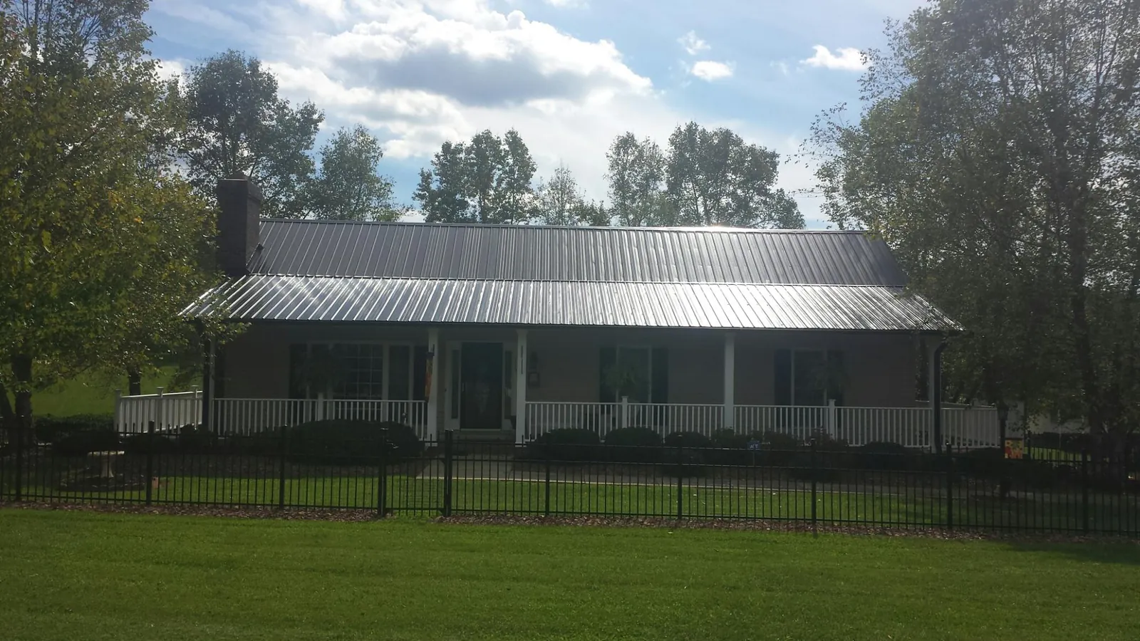 Gray metal roof on a brick ranch with a full width front porch — Gutter Guard Installation work by our crew in Darrington