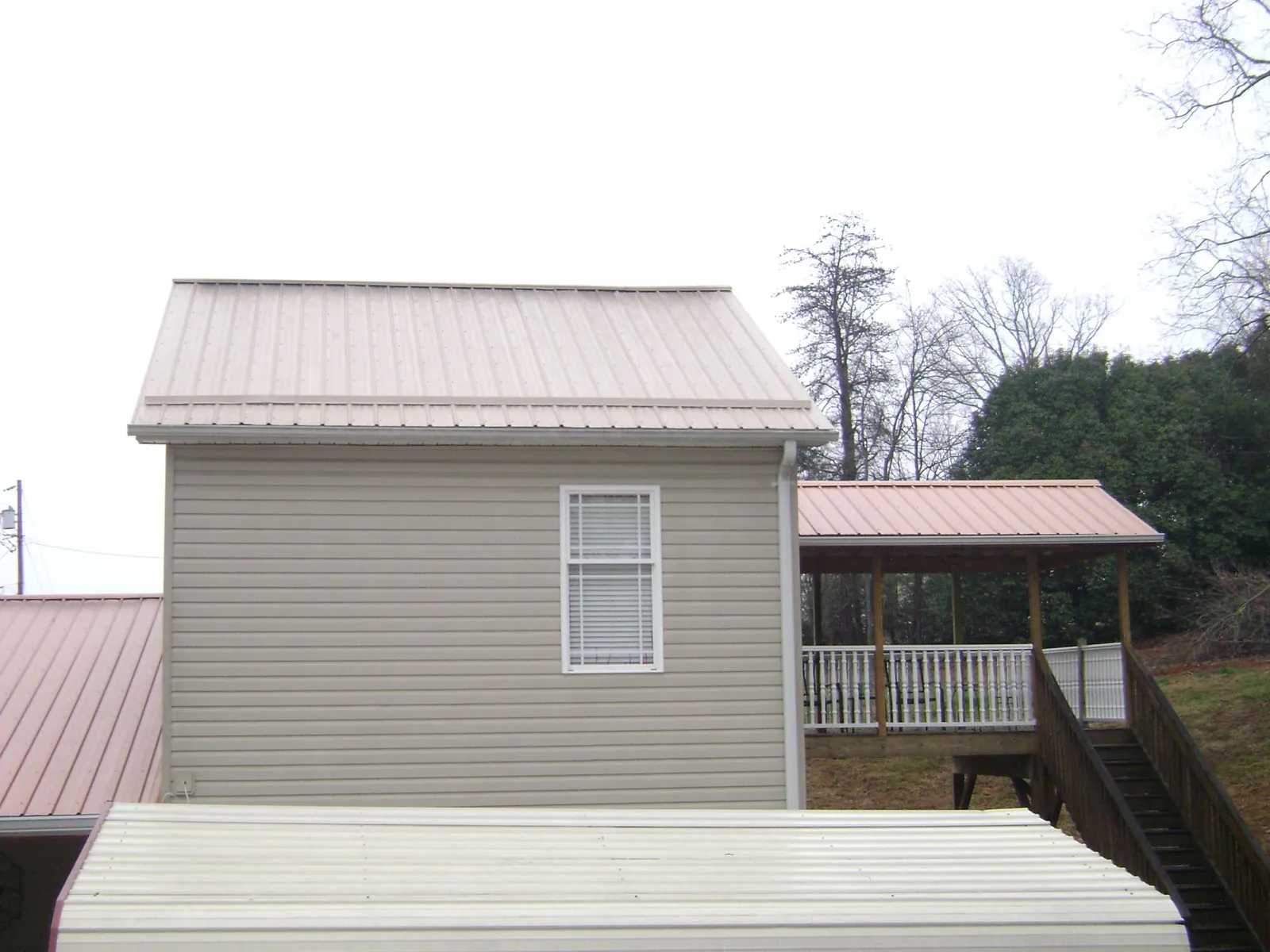 Tan metal roofs on a two story addition and attached porch, from a Roof Replacement job in Darrington