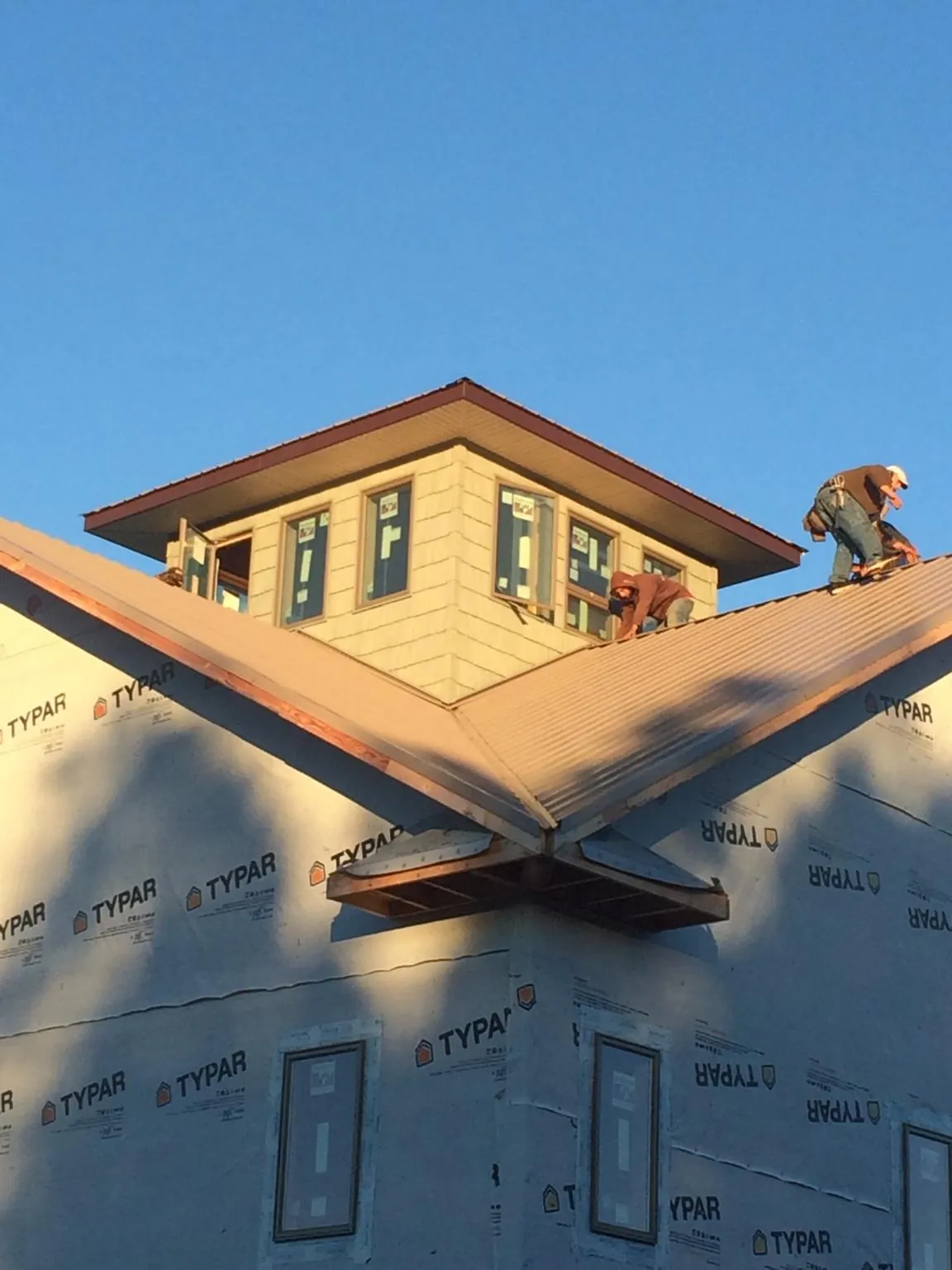 Roofers working around a rooftop cupola on a new metal roof at sunset — Roof Waterproofing in Darrington by Roofing Brothers